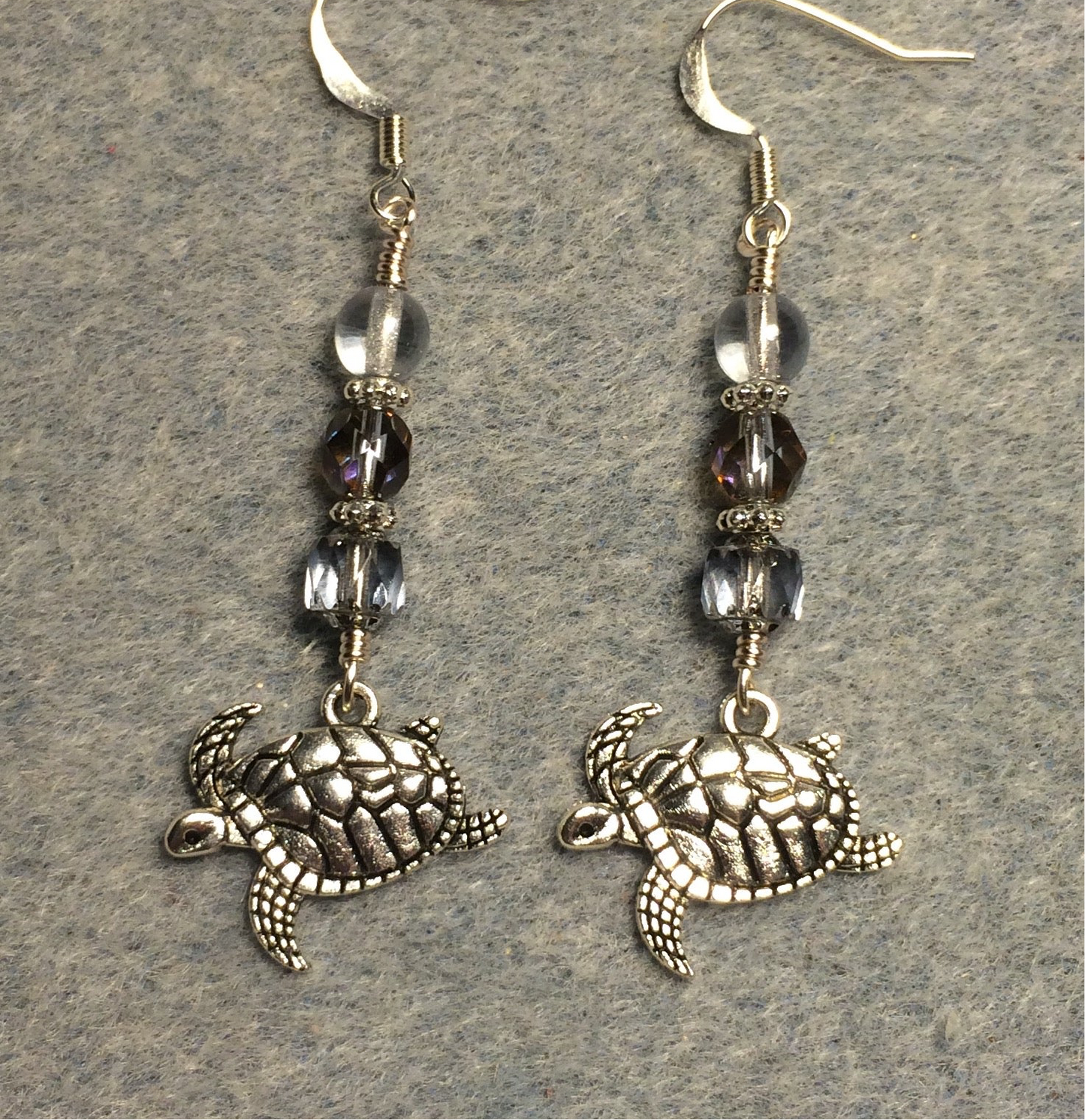 Silver sea turtle charm earrings adorned with light blue Czech glass beads.