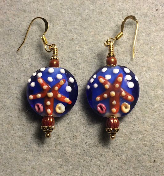 Blue and orange polka dotted lamp work starfish bead earrings adorned with dark orange Chinese crystal beads.
