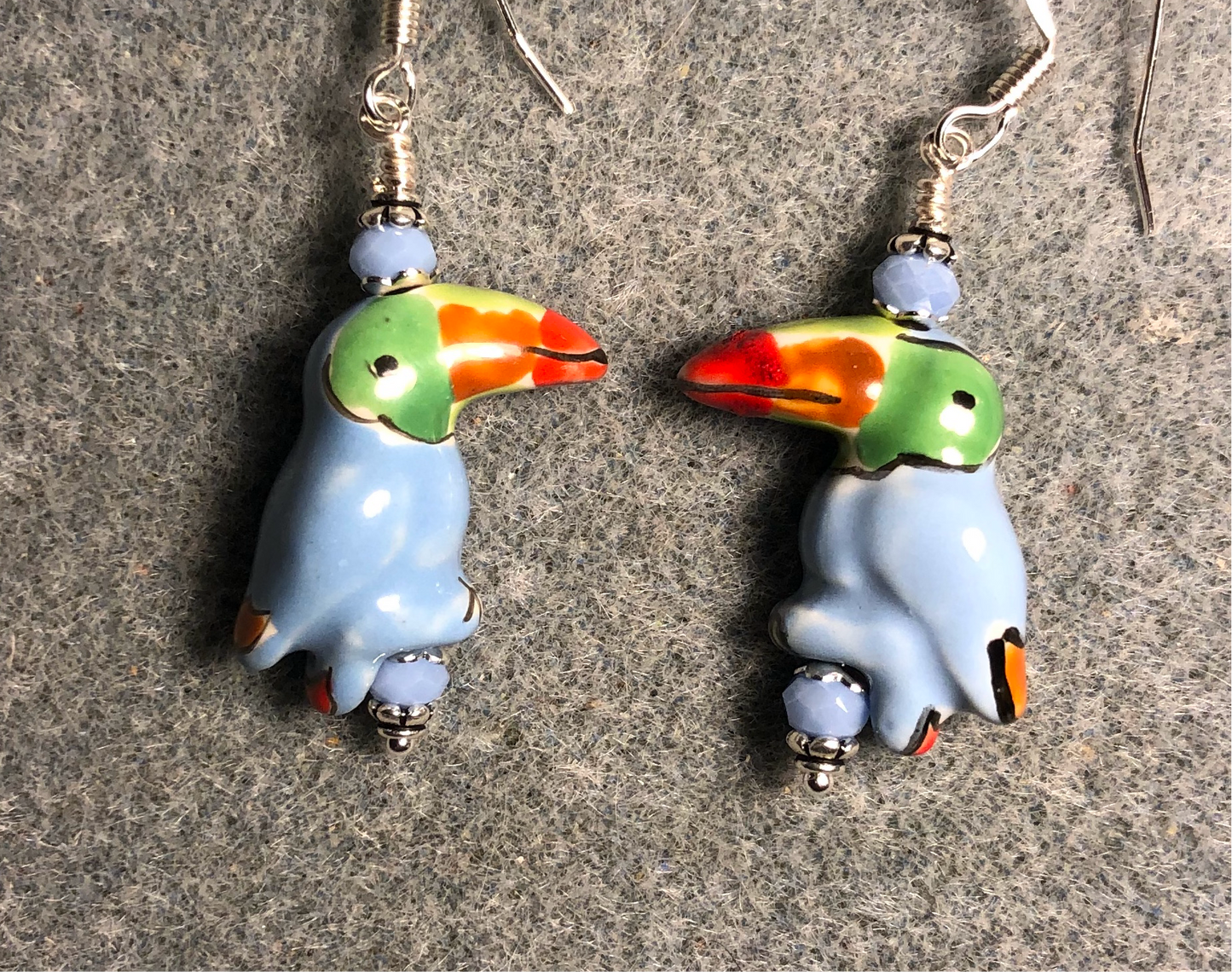 Light blue, green, and red ceramic toucan bead earrings adorned with light blue Chinese crystal beads.