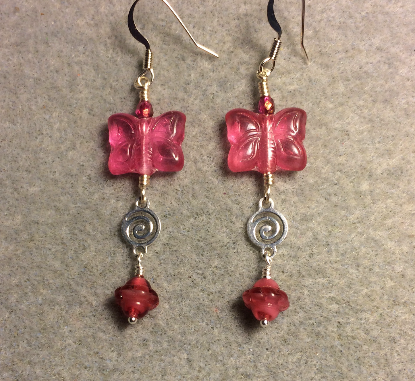 Hot pink Czech glass butterfly bead earrings adorned with silver swirly connectors and hot pink Czech glass daisy beads.