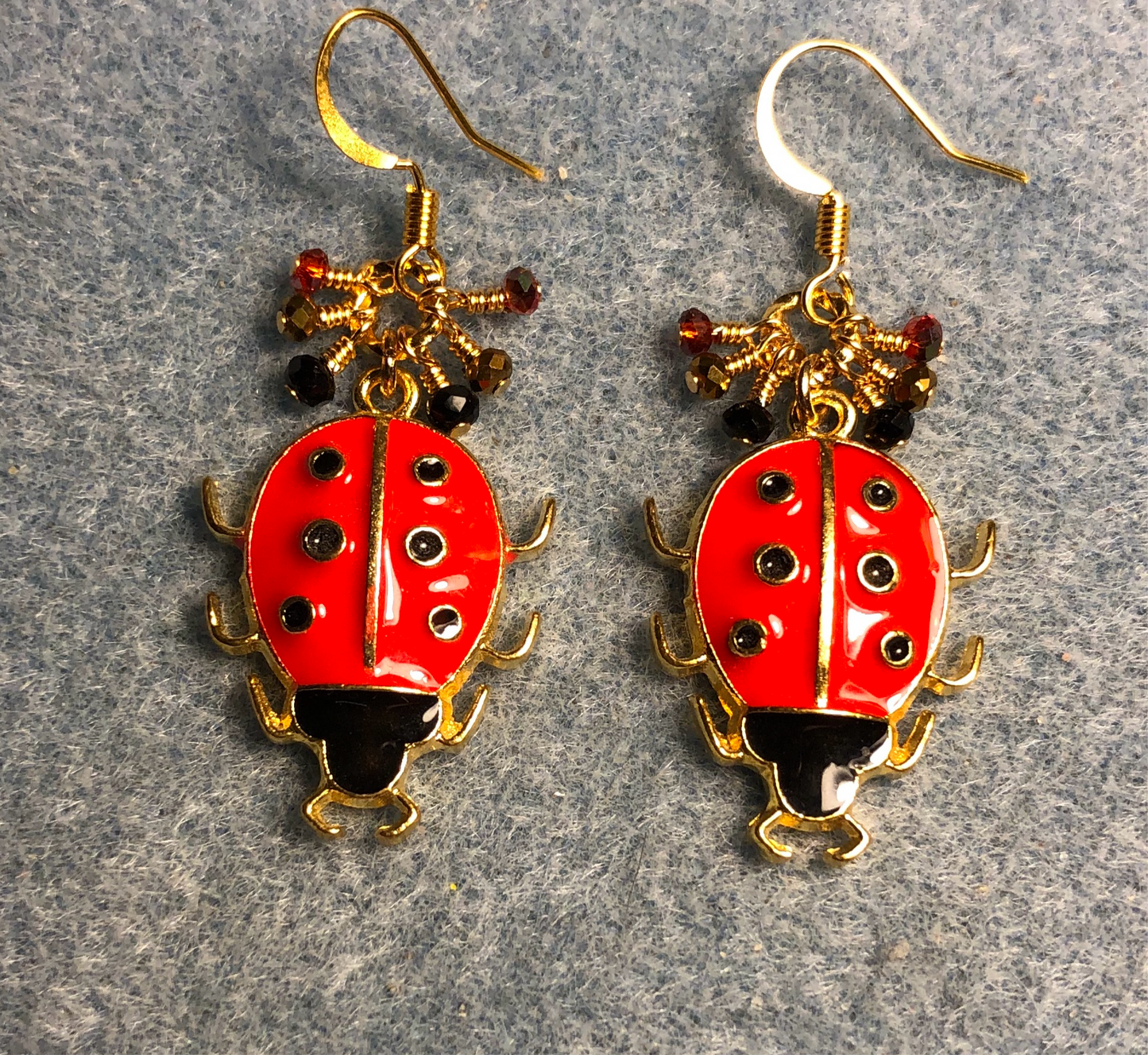 Red and black enamel ladybug charm earrings adorned with tiny dangling red, black, and gold Chinese crystal beads.