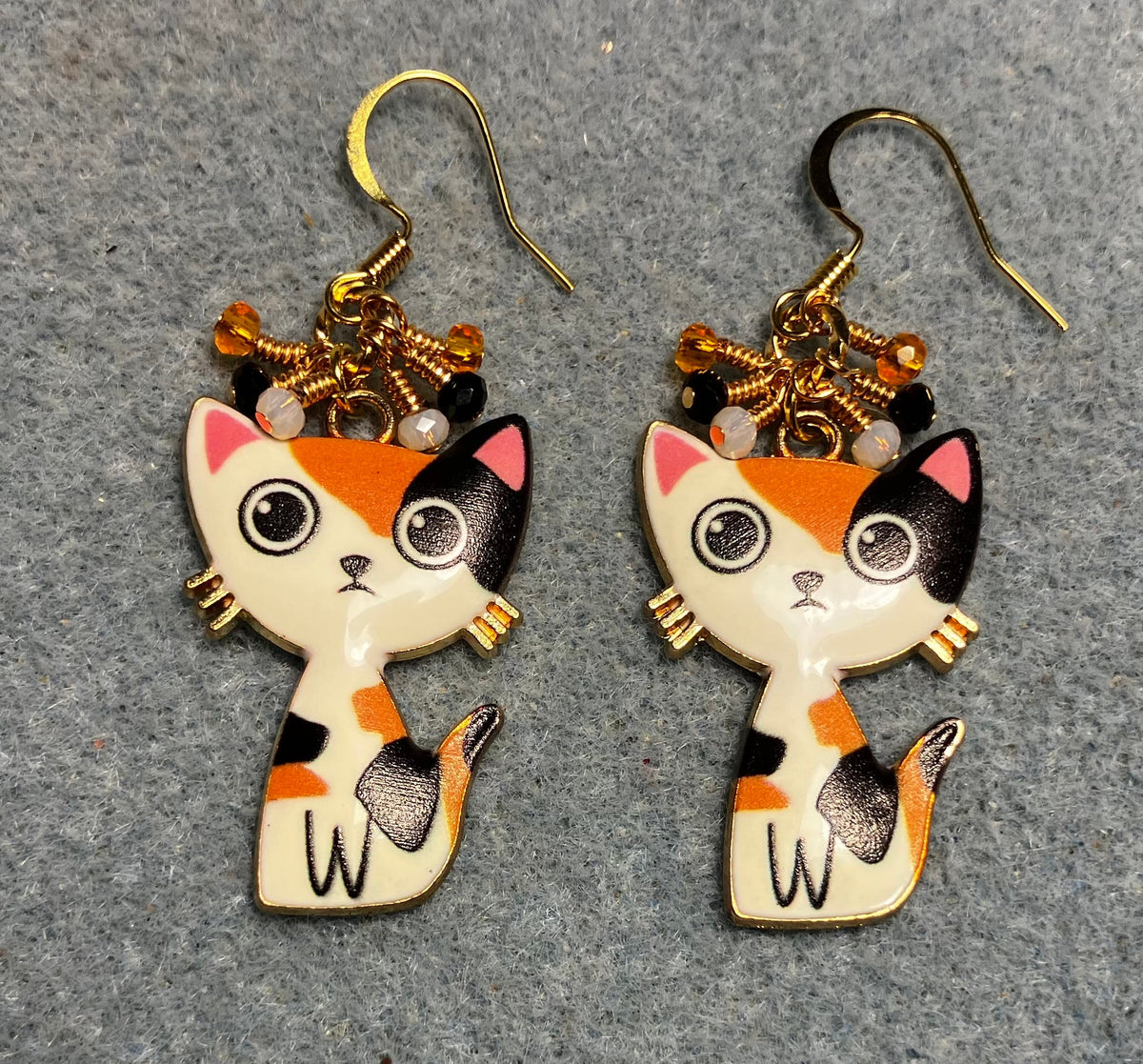 Orange, black, and white enamel calico cat charm earrings adorned with tiny dangling orange, black, and white Chinese crystal beads.
