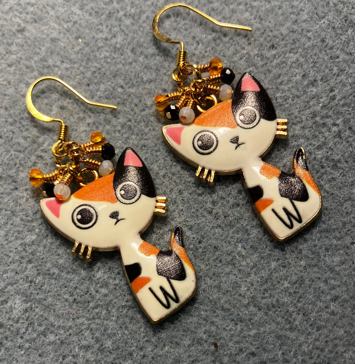 Orange, black, and white enamel calico cat charm earrings adorned with tiny dangling orange, black, and white Chinese crystal beads.