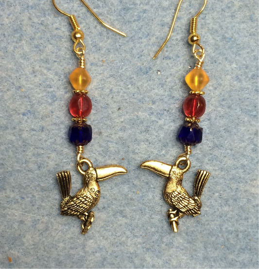 Gold toucan charm earrings adorned with blue, red, and yellow Czech glass beads