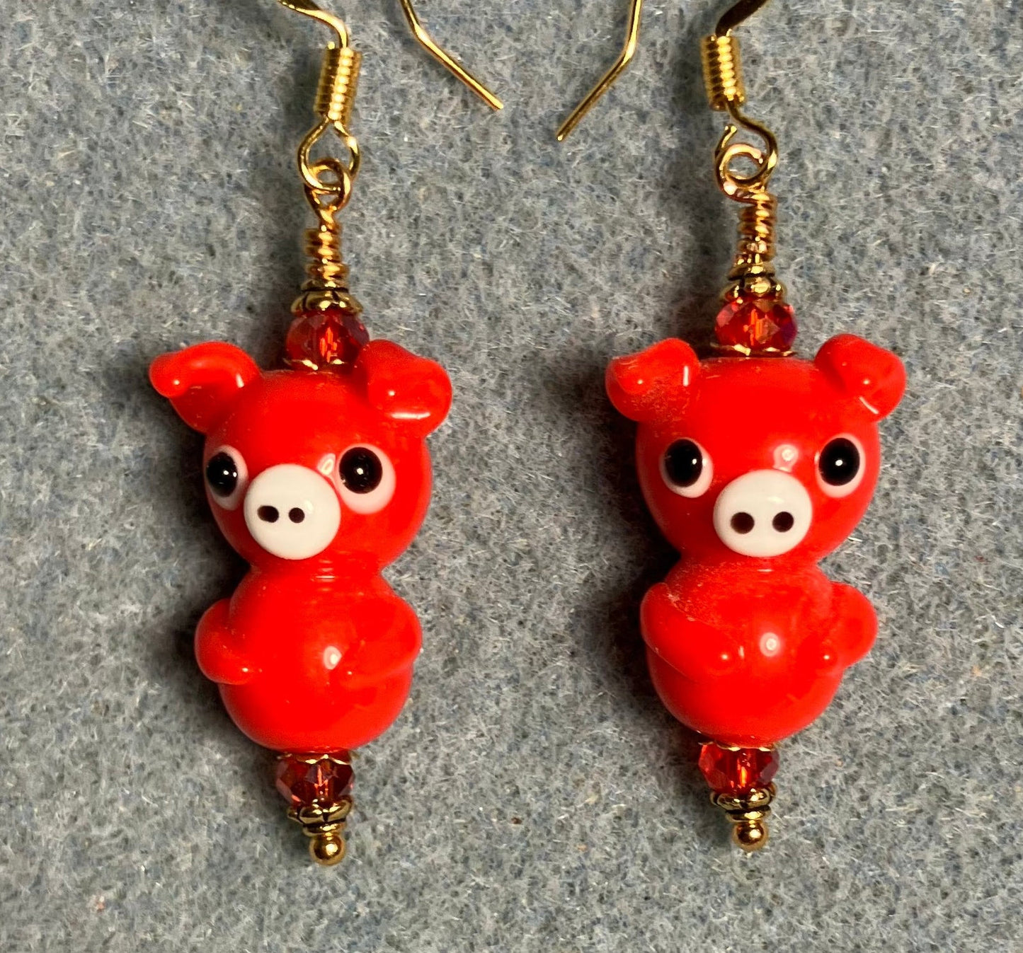 Red lamp work standing pig bead earrings adorned with red Chinese crystal beads.