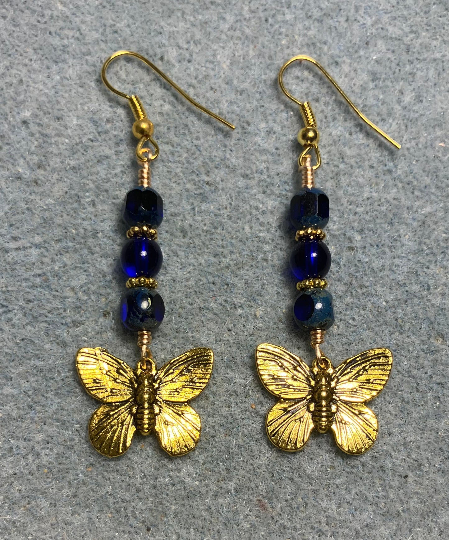 Gold butterfly charm earrings adorned with cobalt blue Czech glass beads.