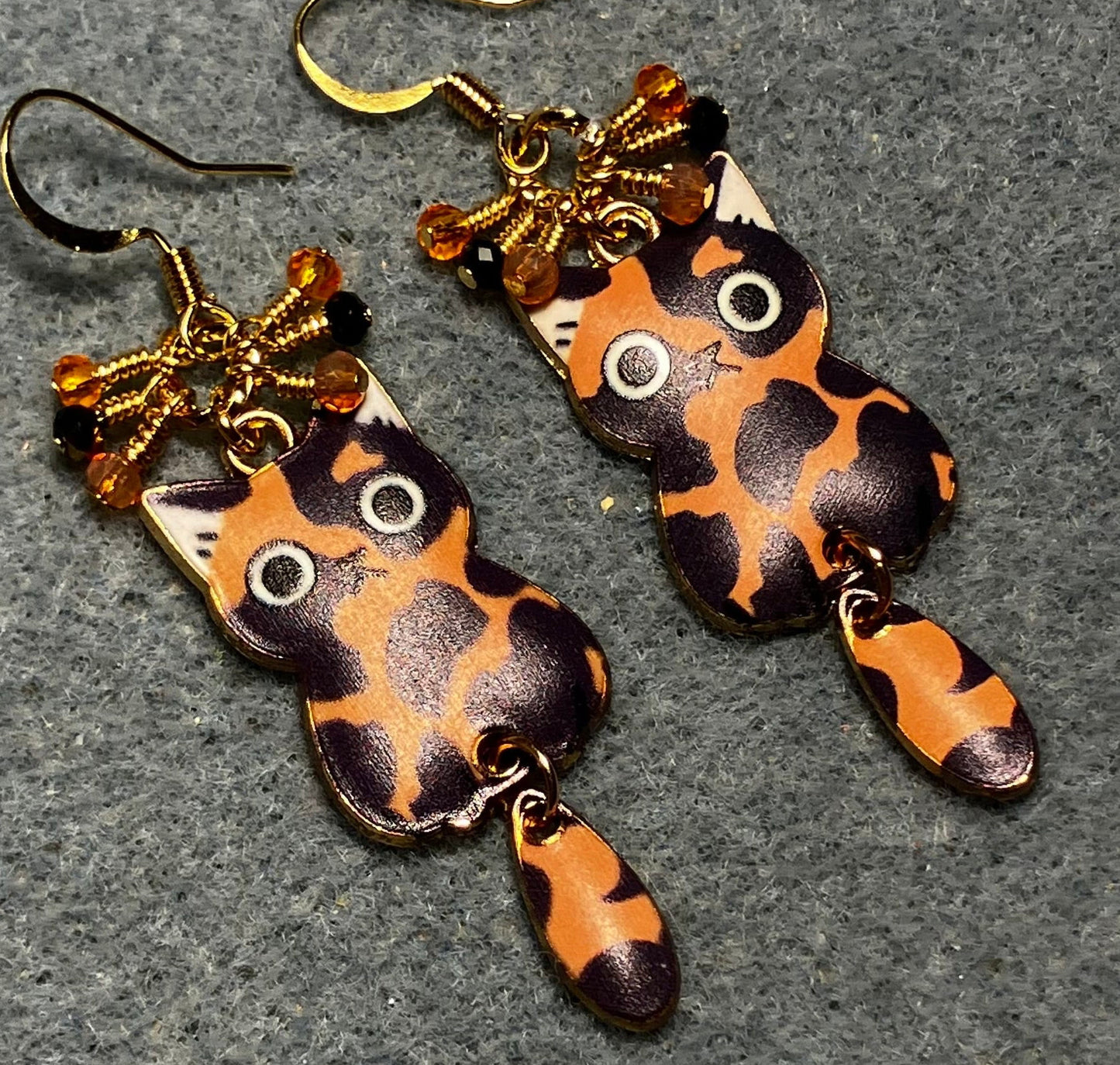 Orange, black, and white enamel calico cat charm earrings adorned with tiny dangling orange and black Chinese crystal beads.