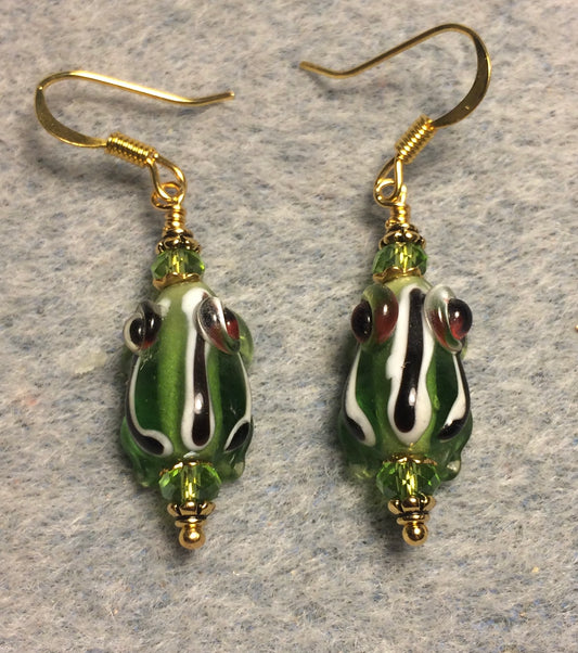 Very small olive green with black and white stripes lamp work frog bead earrings adorned with olive green Chinese crystal beads.