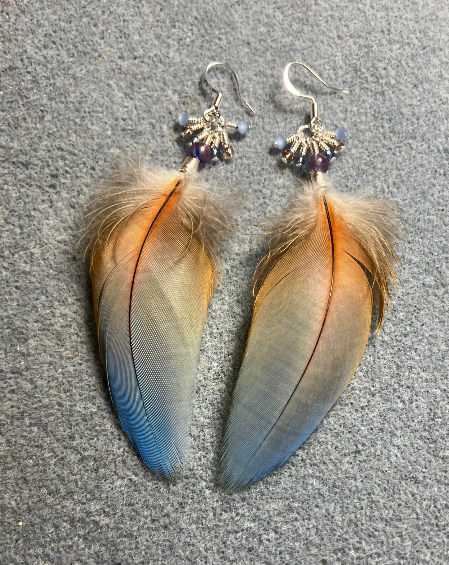 Light blue and peach macaw feather earrings adorned with blue Czech glass beads and tiny dangling light blue and peach Chinese crystal beads.
