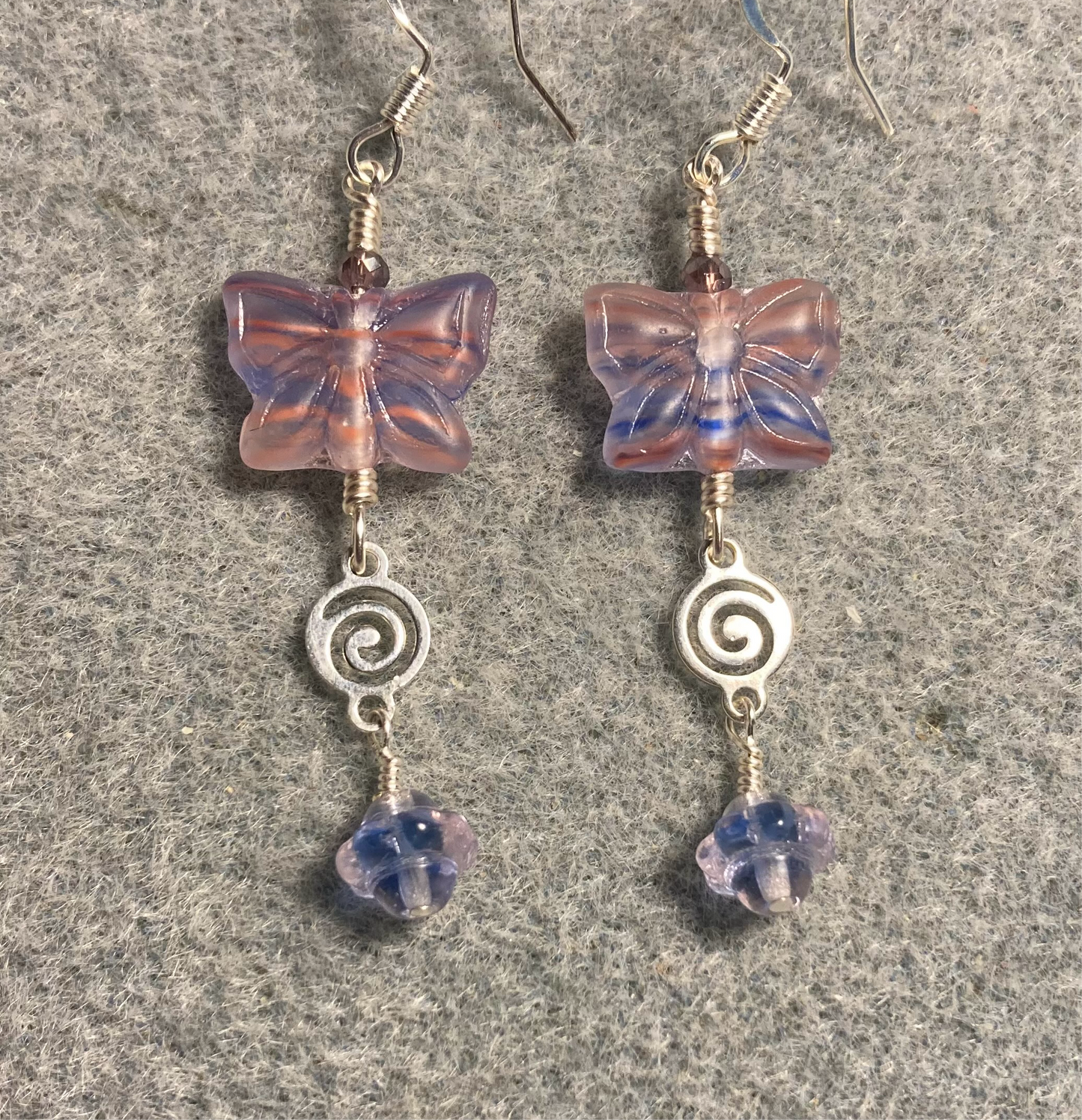 Purple, blue, and pink Czech glass butterfly bead earrings adorned with silver swirly connectors and purple, blue, and pink Czech glass Saturn beads.