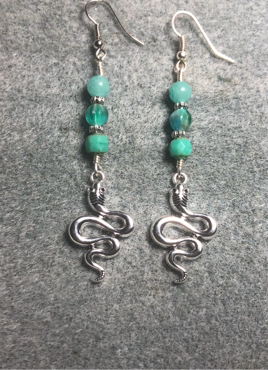 Silver coiled snake charm earrings adorned with milky turquoise Czech glass beads.