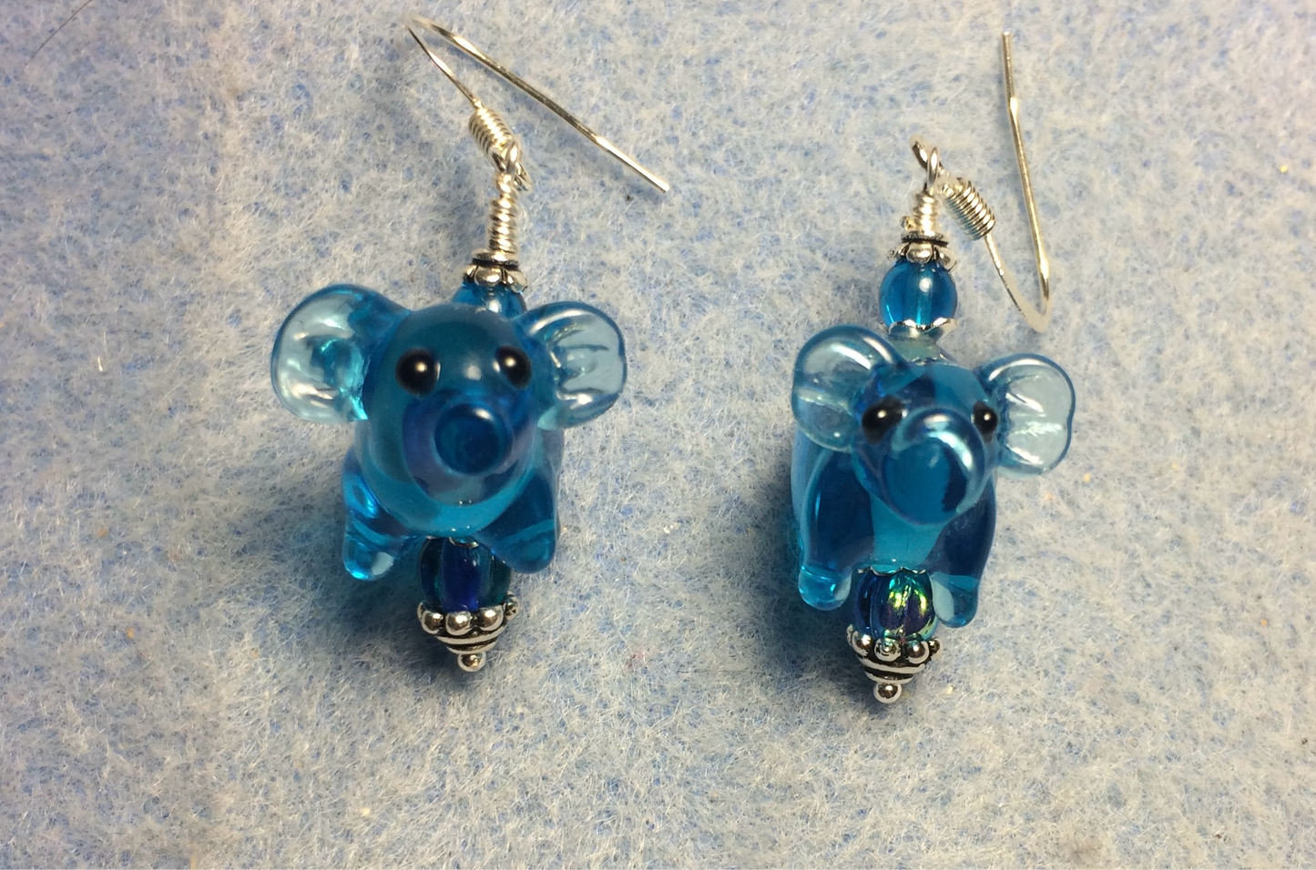 Translucent turquoise lamp work pig bead earrings adorned with turquoise Czech glass beads.