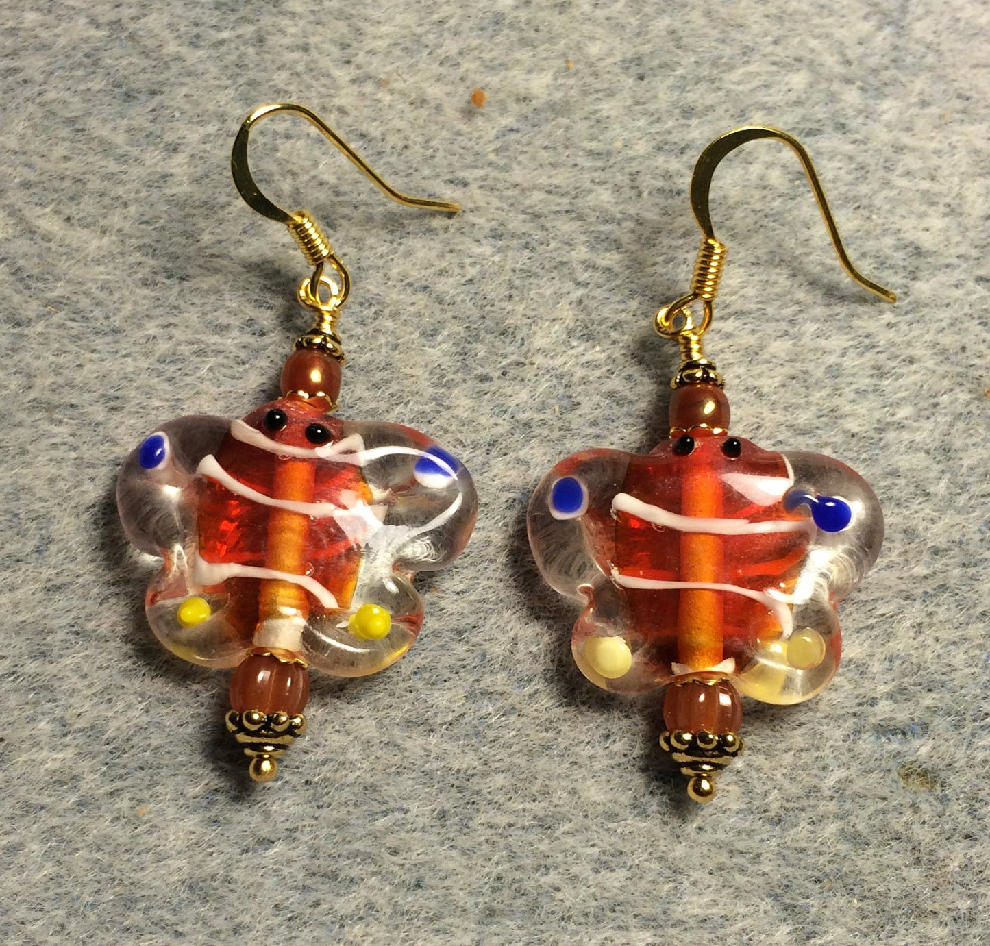 Orange and blue lamp work butterfly bead earrings adorned with dark orange Czech glass beads.