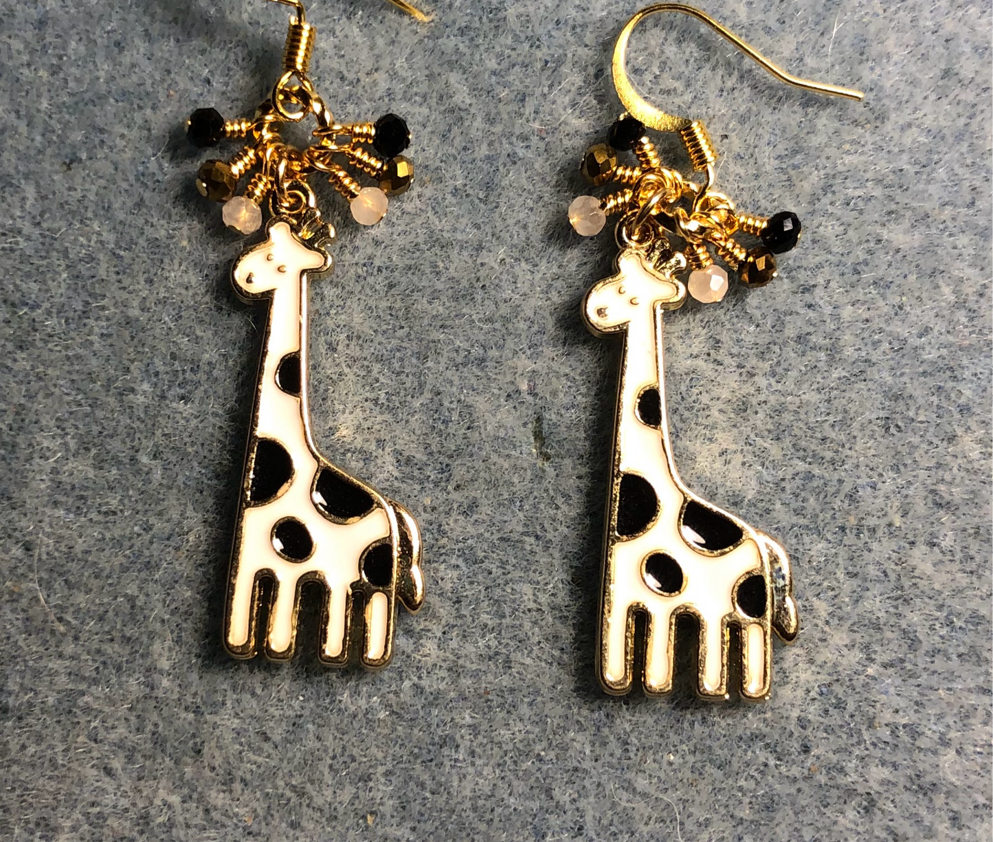 White and black enamel spotted giraffe charm earrings adorned with tiny dangling white, black, and gold Chinese crystal beads.