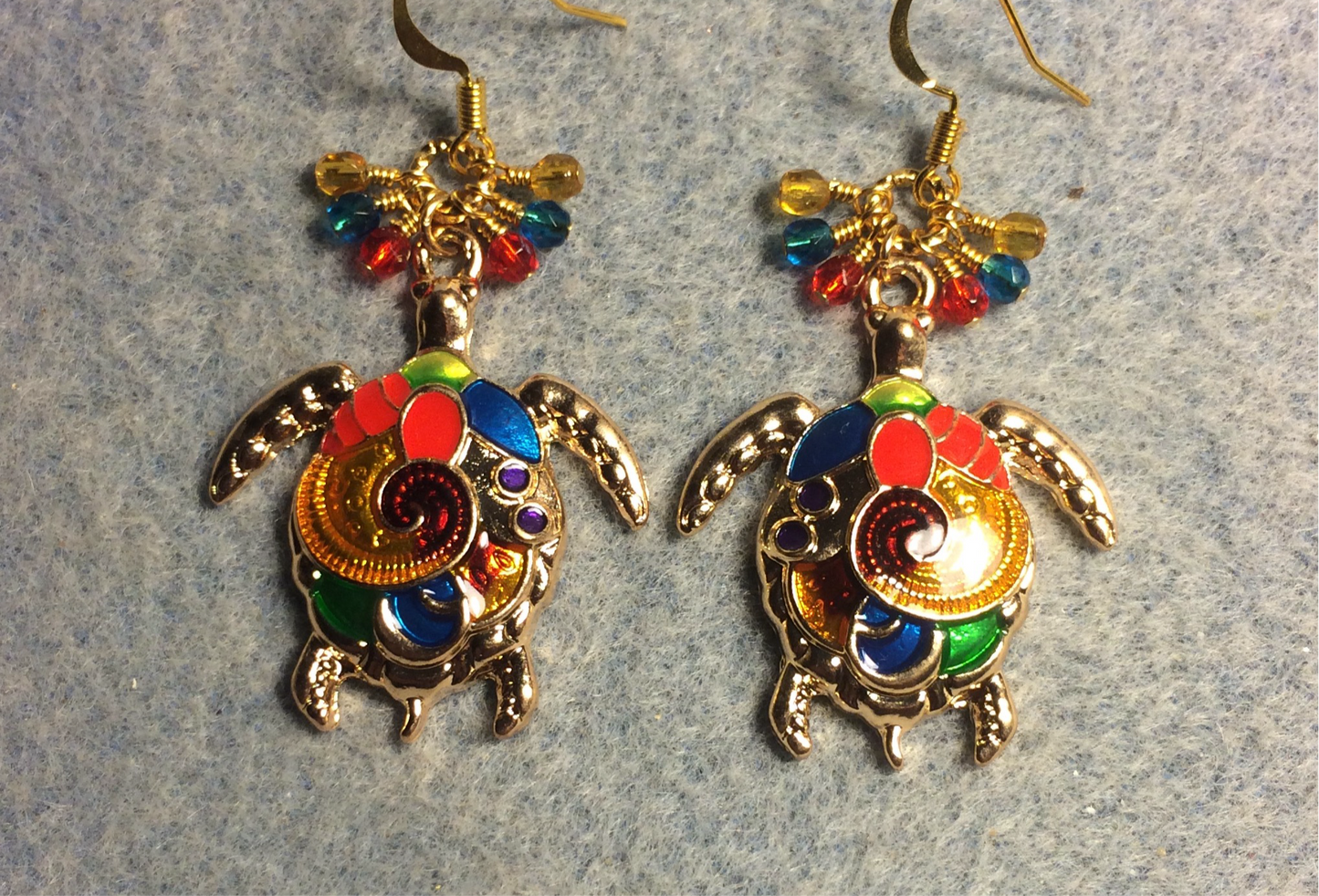 Colorful enamel sea turtle charm earrings adorned with small dangling red, turquoise, and amber Czech glass beads.