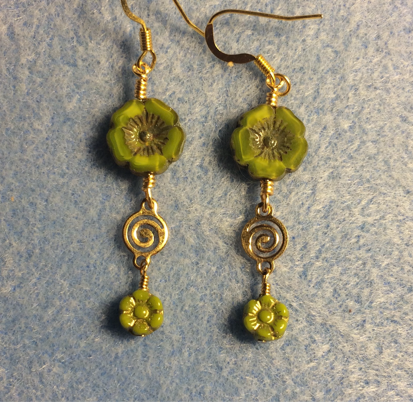 Yellow green Czech glass pansy bead earrings adorned with gold swirly connectors and tiny yellow green Czech glass daisy beads.