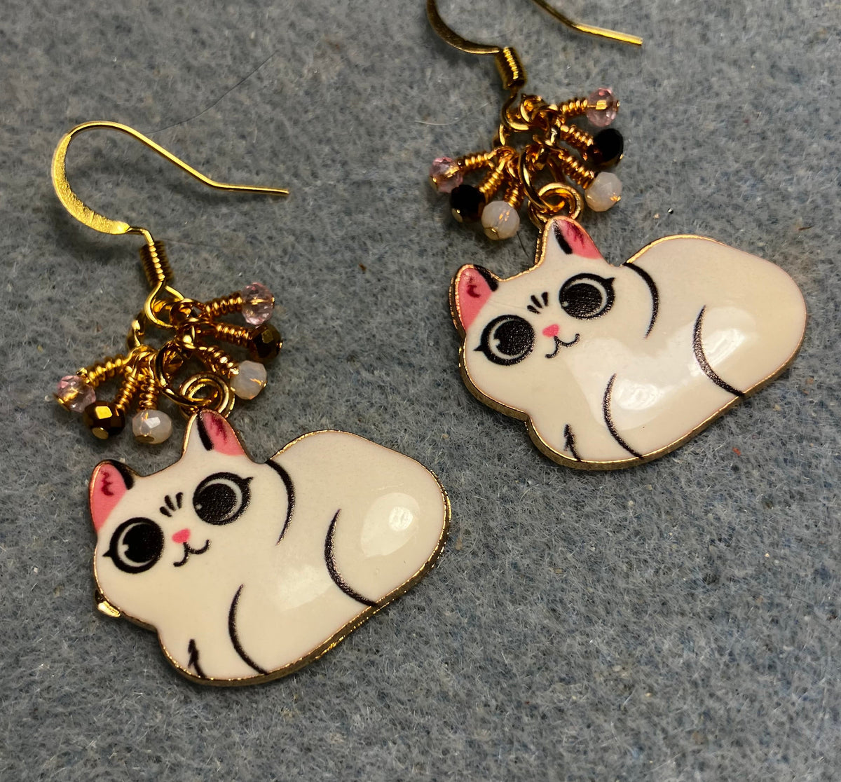 White, black, and pink enamel cat charm earrings adorned with tiny dangling white, black, and pink Chinese crystal beads.