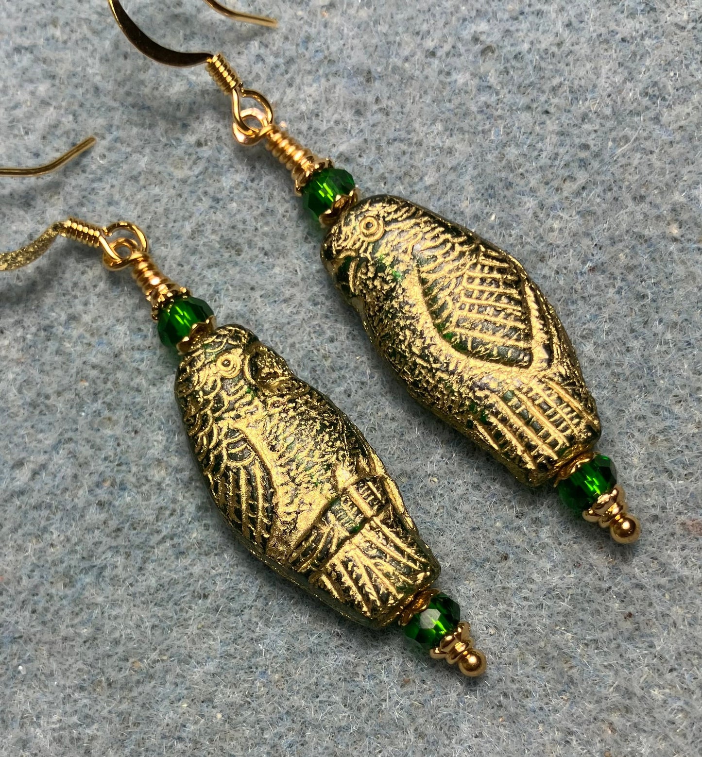 Large green (with gold wash) Czech glass parrot bead earrings adorned with green Chinese crystal beads.