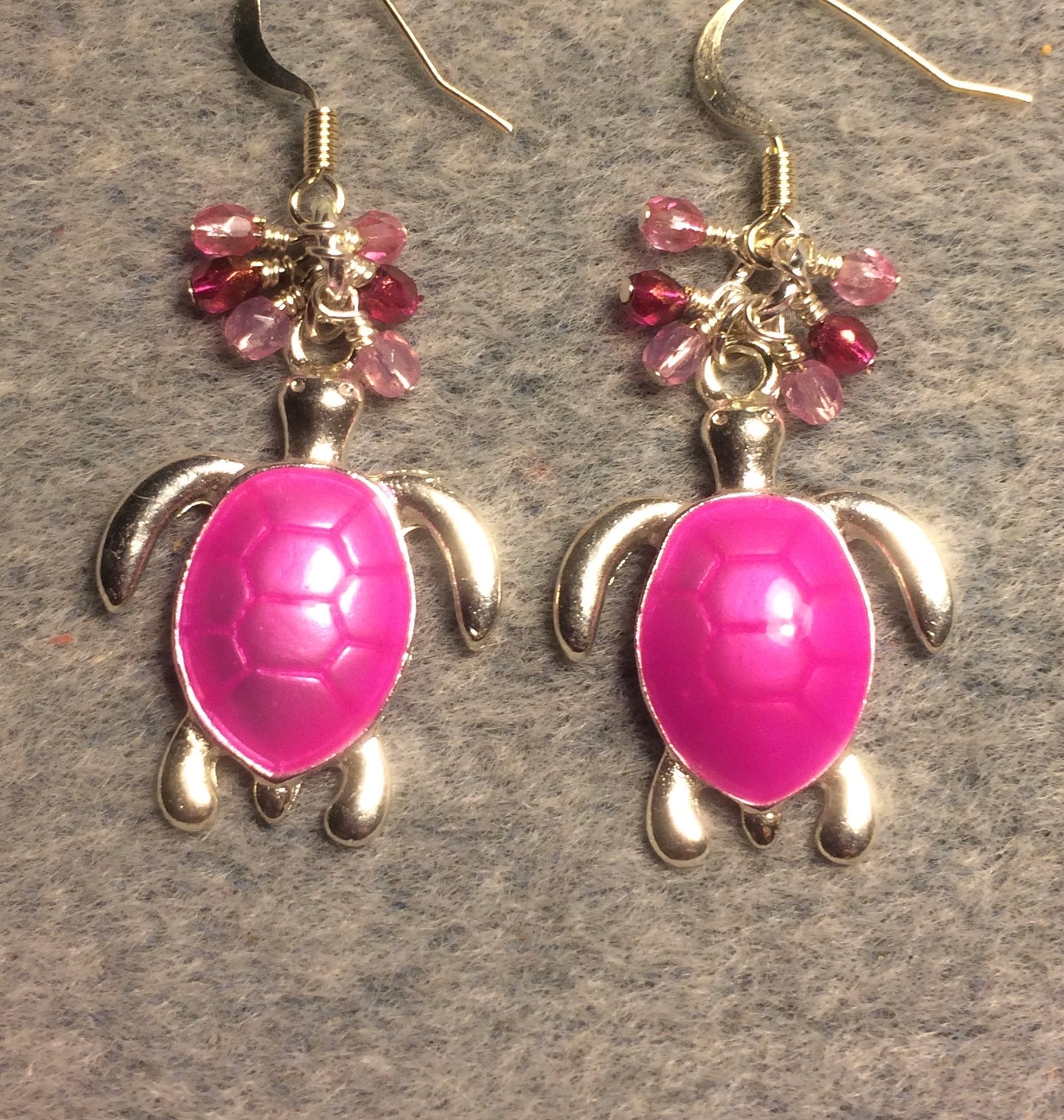 Bright pink enamel sea turtle charm earrings adorned with small dangling pink Czech glass beads.