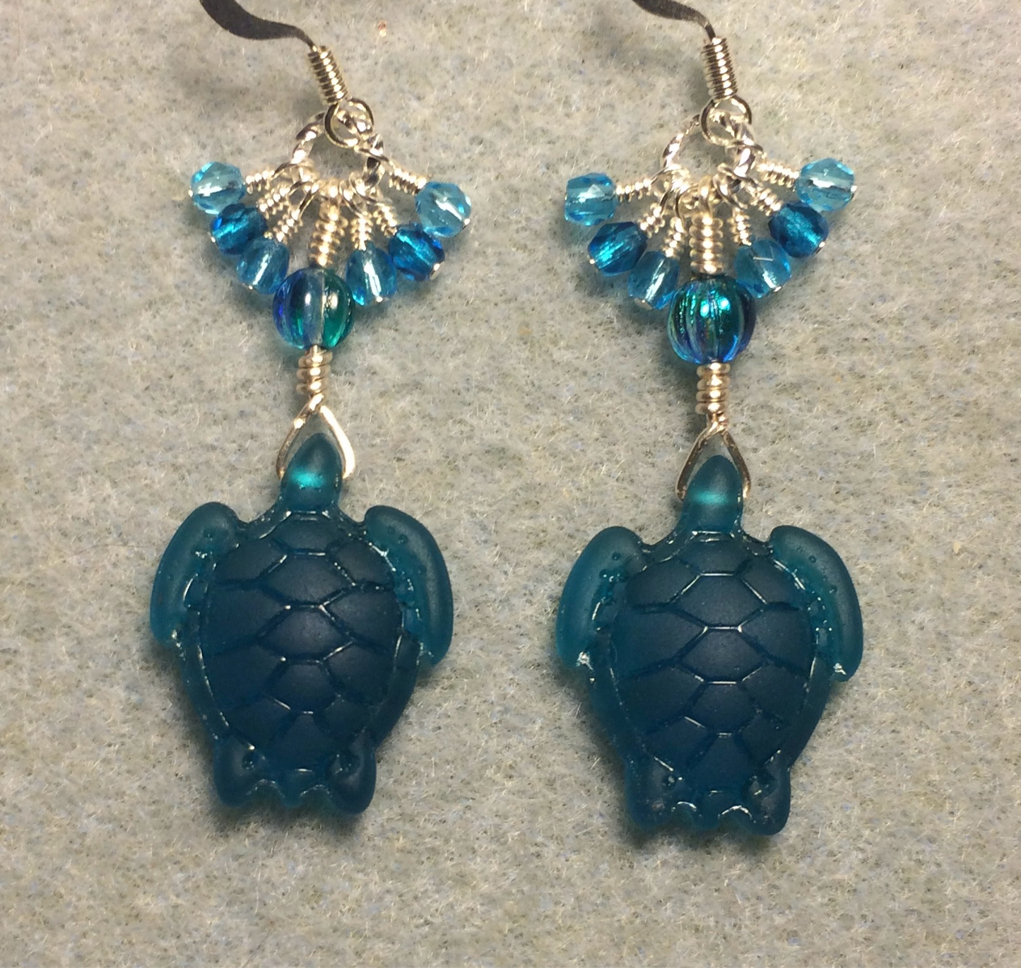 Dark turquoise sea glass sea turtle bead earrings adorned with turquoise Czech glass beads and small dangling turquoise Czech glass beads.