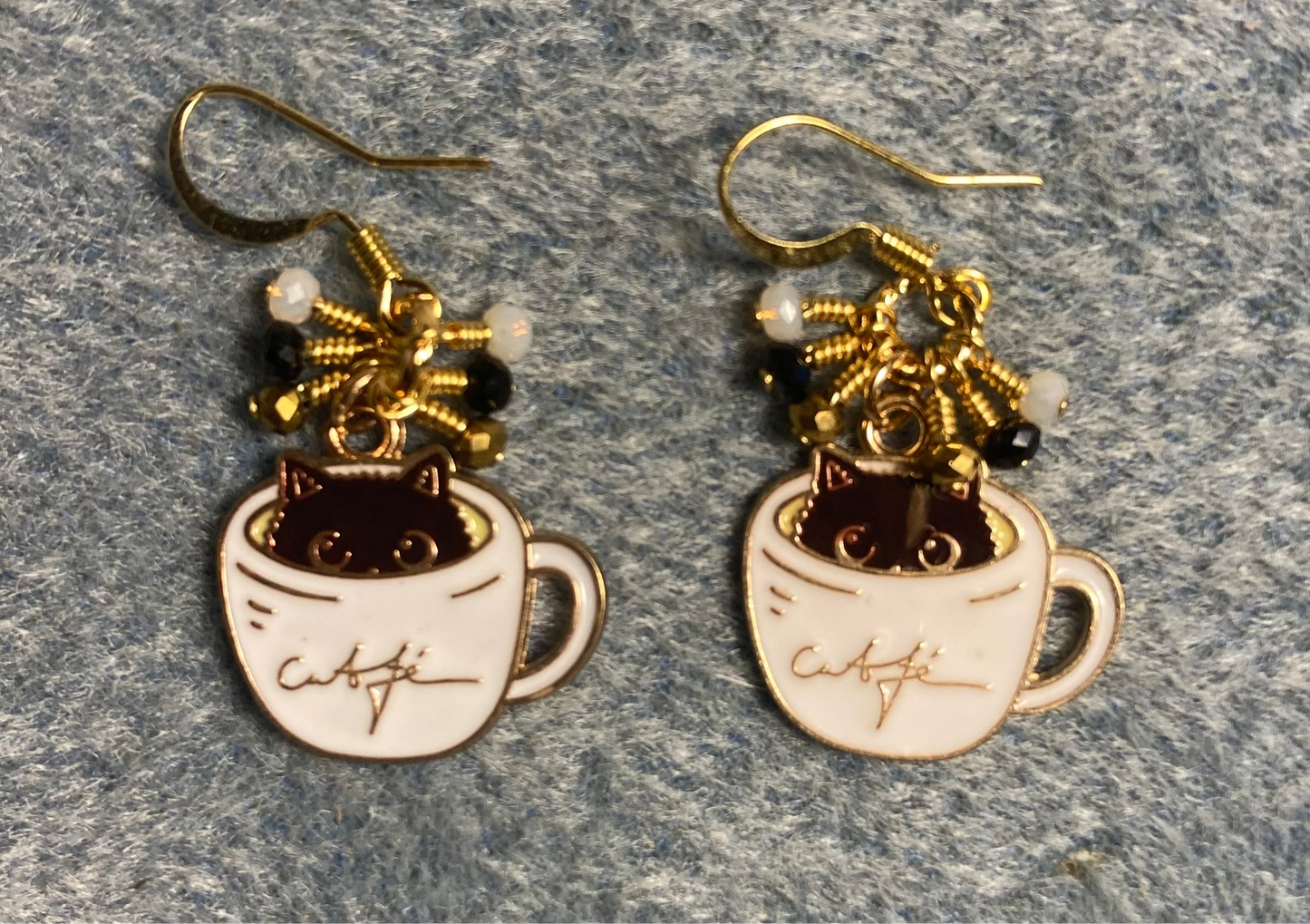 Black, white, and gold enamel cat charm earrings adorned with tiny dangling black, white, and gold Chinese crystal beads.