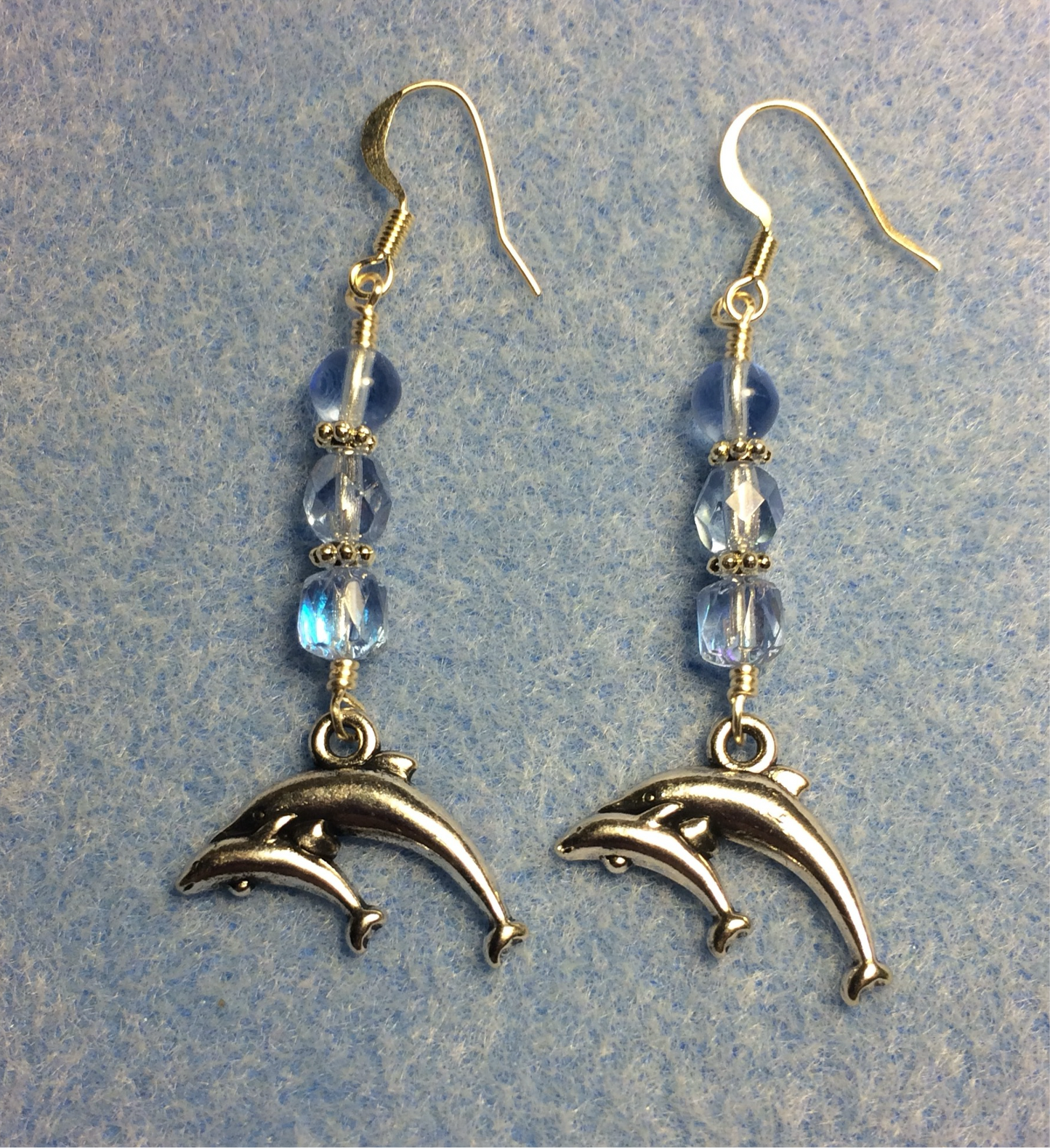 Silver pair of dolphins charm earrings adorned with light blue Czech glass beads
