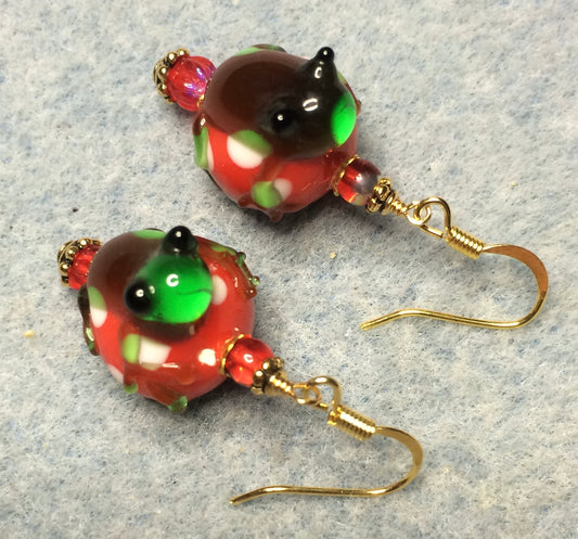 Red, green, and brown lamp work frog bead earrings adorned with red Czech glass beads.