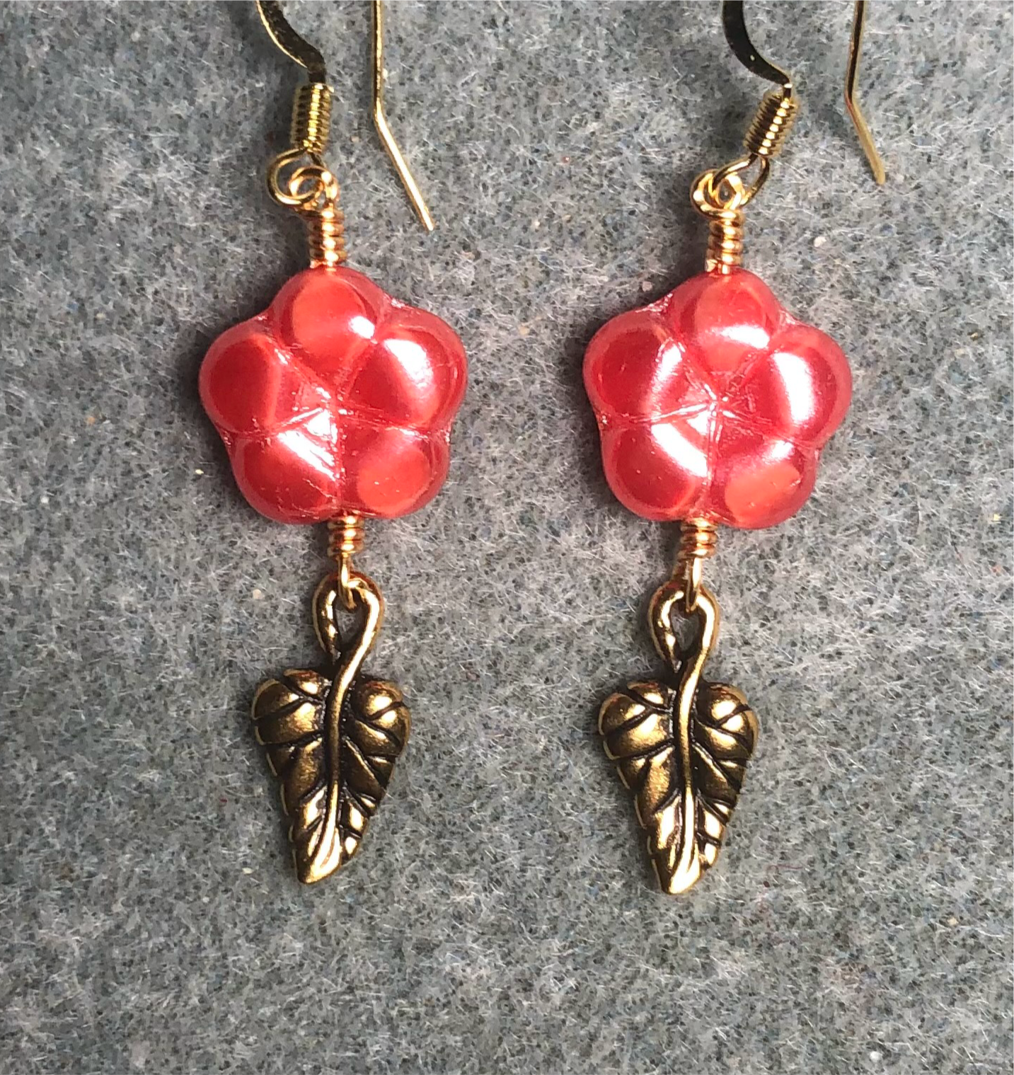 Reddish pink Czech glass puffy flower bead earrings adorned with gold Tierracast leaf charms.