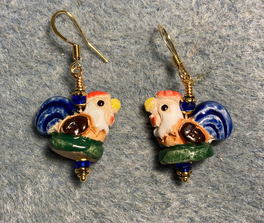 Small tan, brown, dark blue, and green ceramic chicken bead earrings adorned with dark blue Chinese crystal beads.