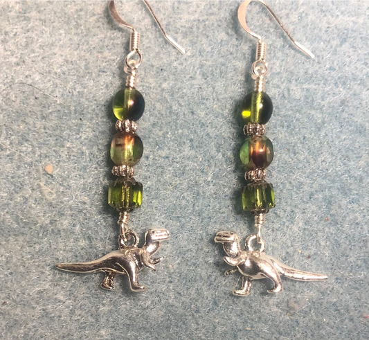 Silver T rex dinosaur charm earrings adorned with olive green Czech glass beads