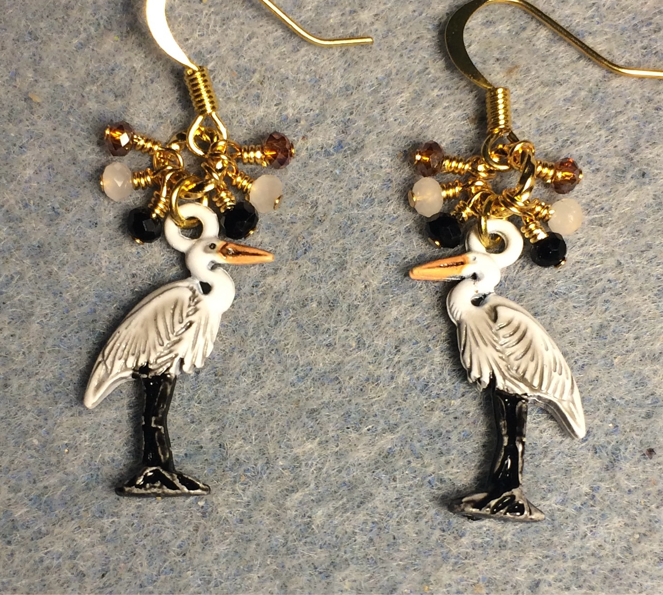 White, black, and orange enamel heron charm earrings adorned with tiny dangling white, black, and orange Chinese crystal beads.