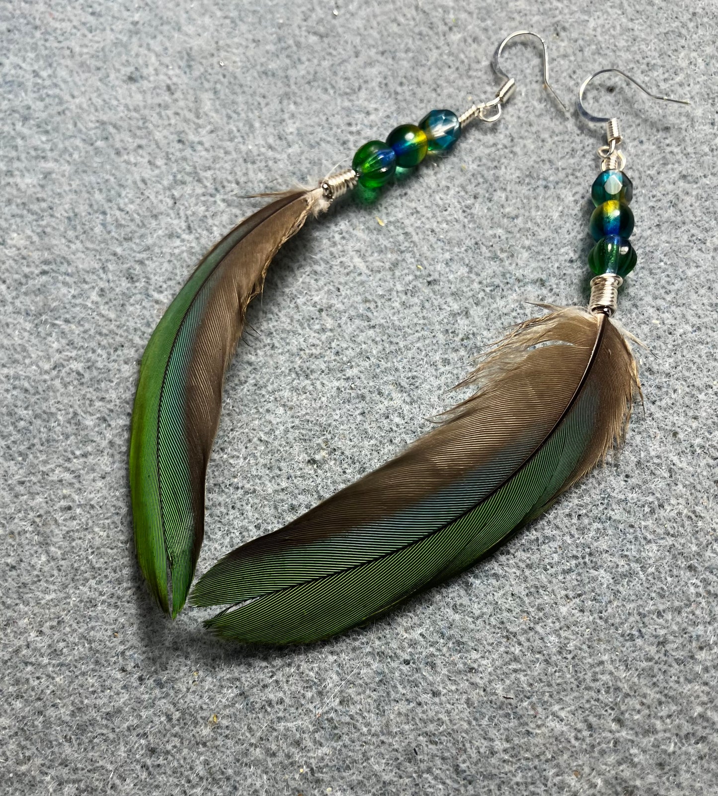 Bluish green mini macaw feather earrings adorned with green and teal Czech glass beads.