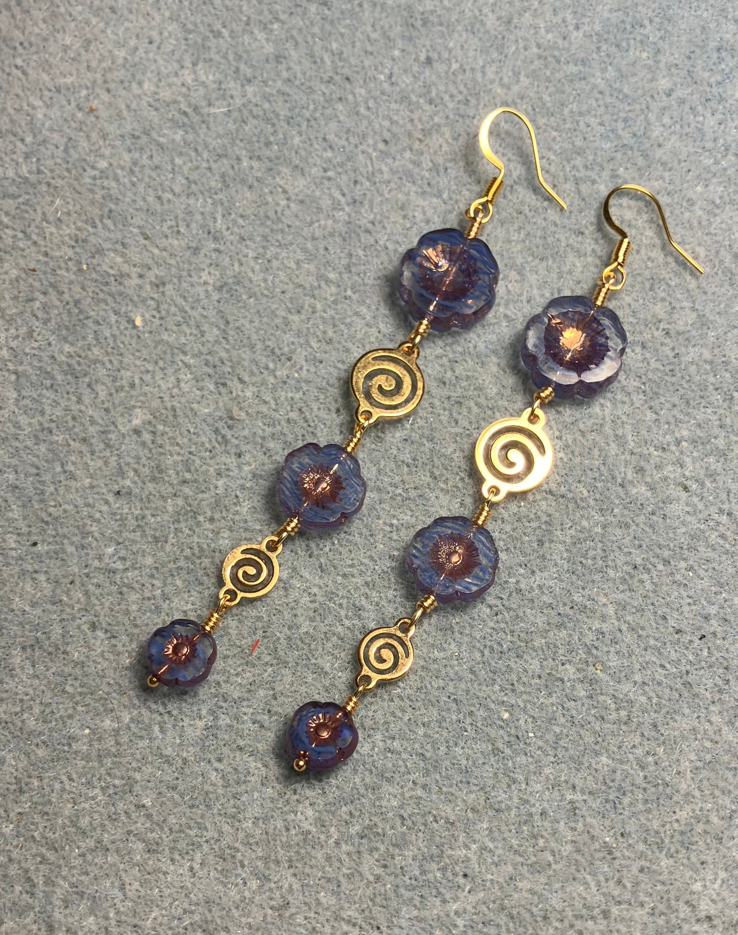 Extra long blue striped flower bead earrings made with three sizes of blue striped Czech glass pansy beads joined by gold swirly connectors.