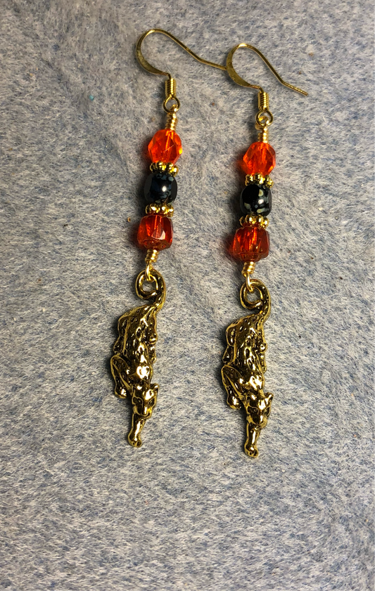 Gold stretching jaguar charm earrings adorned with orange and black Czech glass beads