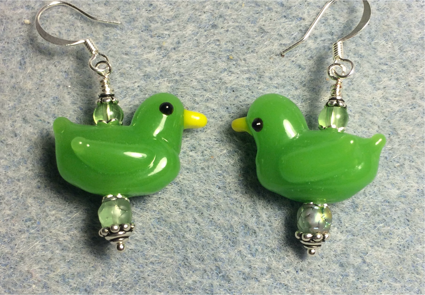 Opaque green lamp work duck bead earrings adorned with green Czech glass beads.