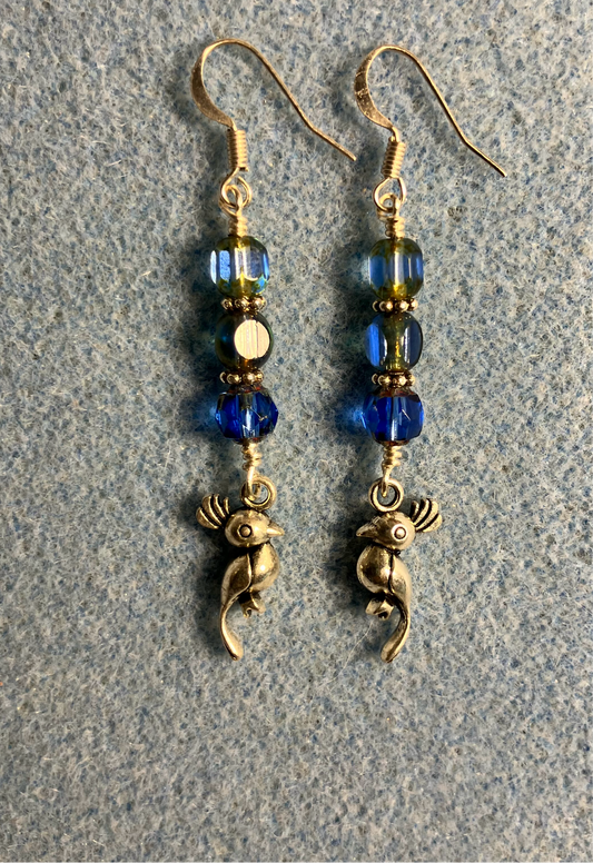 Silver parrot charm earrings adorned with blue Czech glass beads.
