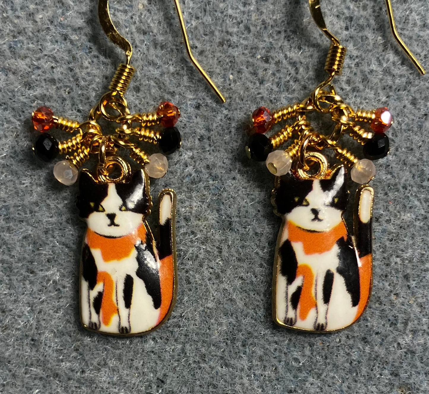 Black, orange, and white enamel calico cat charm earrings adorned with tiny dangling black, orange, and white  Chinese crystal beads.