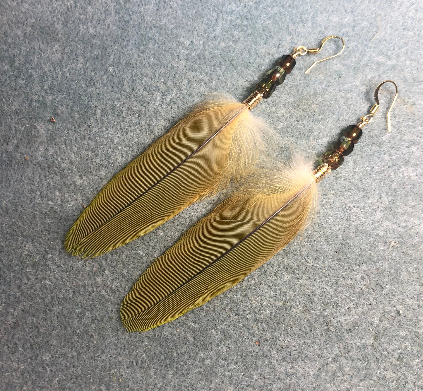 Olive green red-fronted macaw feather earrings adorned with olive green Czech glass beads.