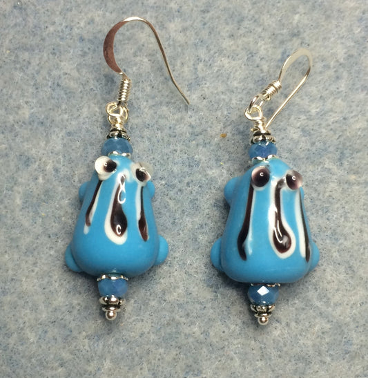 Light blue with black stripes lamp work frog bead earrings adorned with light blue Chinese crystal beads.