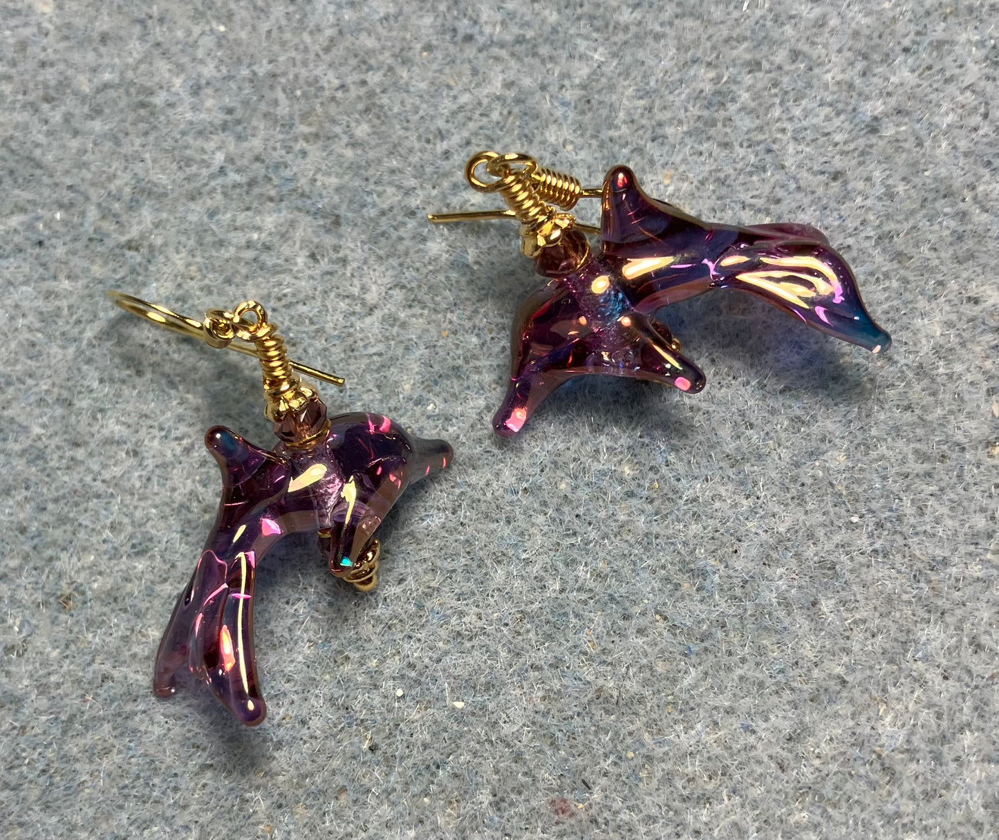 Tiny aurora borealis violet lamp work dolphin bead earrings adorned with tiny violet Chinese crystal beads.