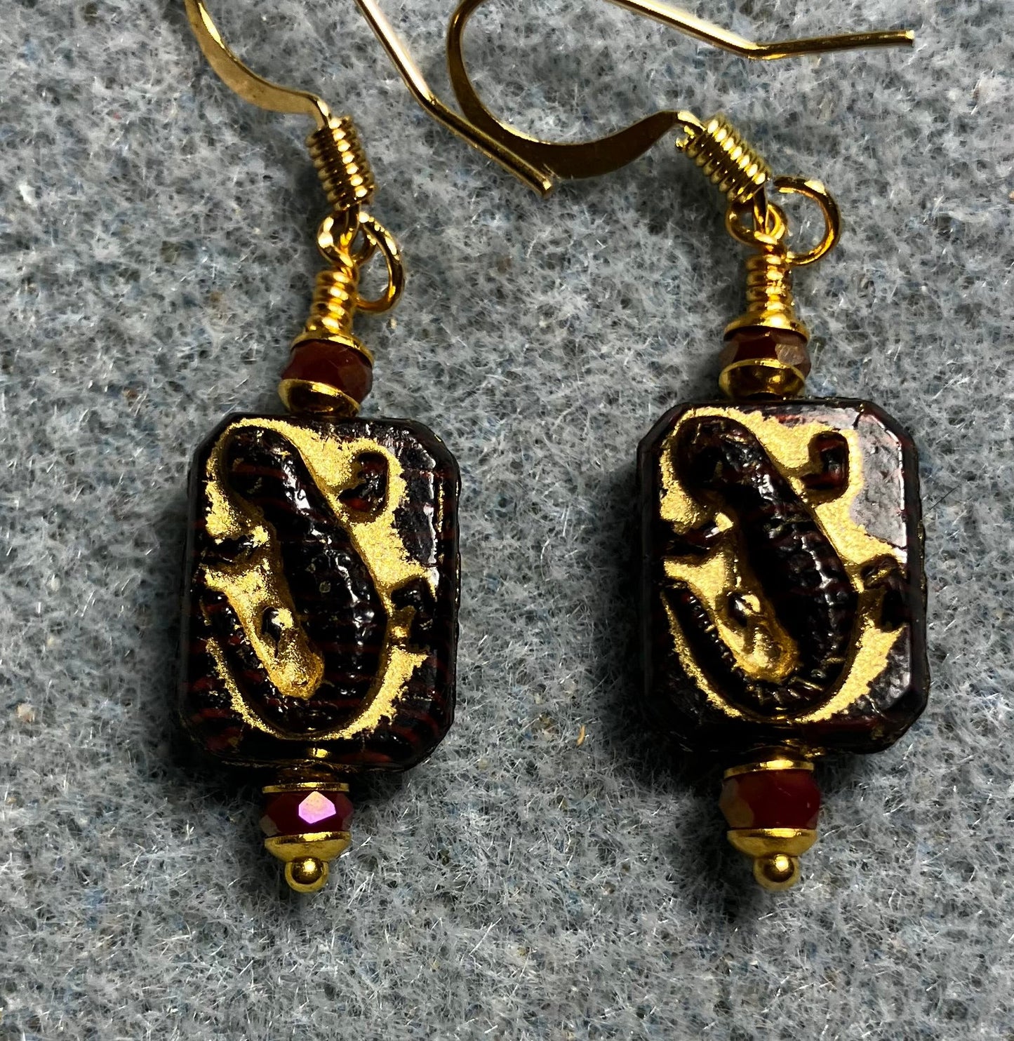 Small dark red and gold Czech glass lizard bead earrings adorned with dark red Chinese crystal beads.