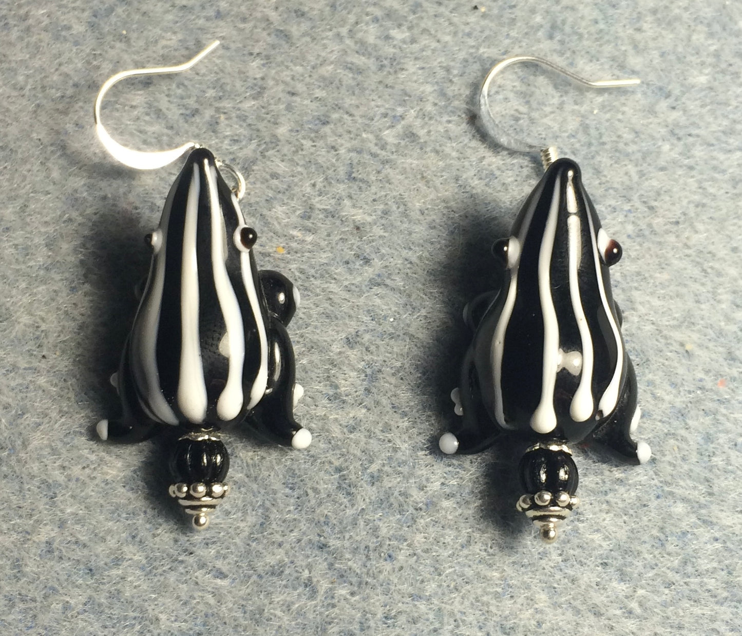 Black with white stripes lamp work frog bead earrings adorned with black Czech glass beads.