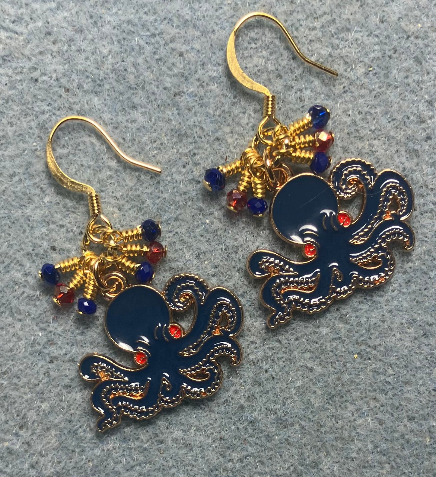 Dark blue, red, and gold enamel octopus charm earrings adorned with tiny dangling dark blue and red Chinese crystal beads.