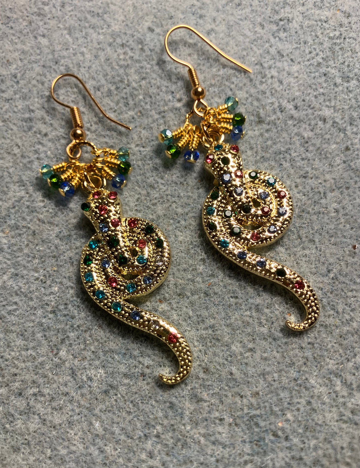 Gold and colored rhinestone coiled snake charm earrings adorned with tiny dangling turquoise, light blue, and dark green Chinese crystal beads.