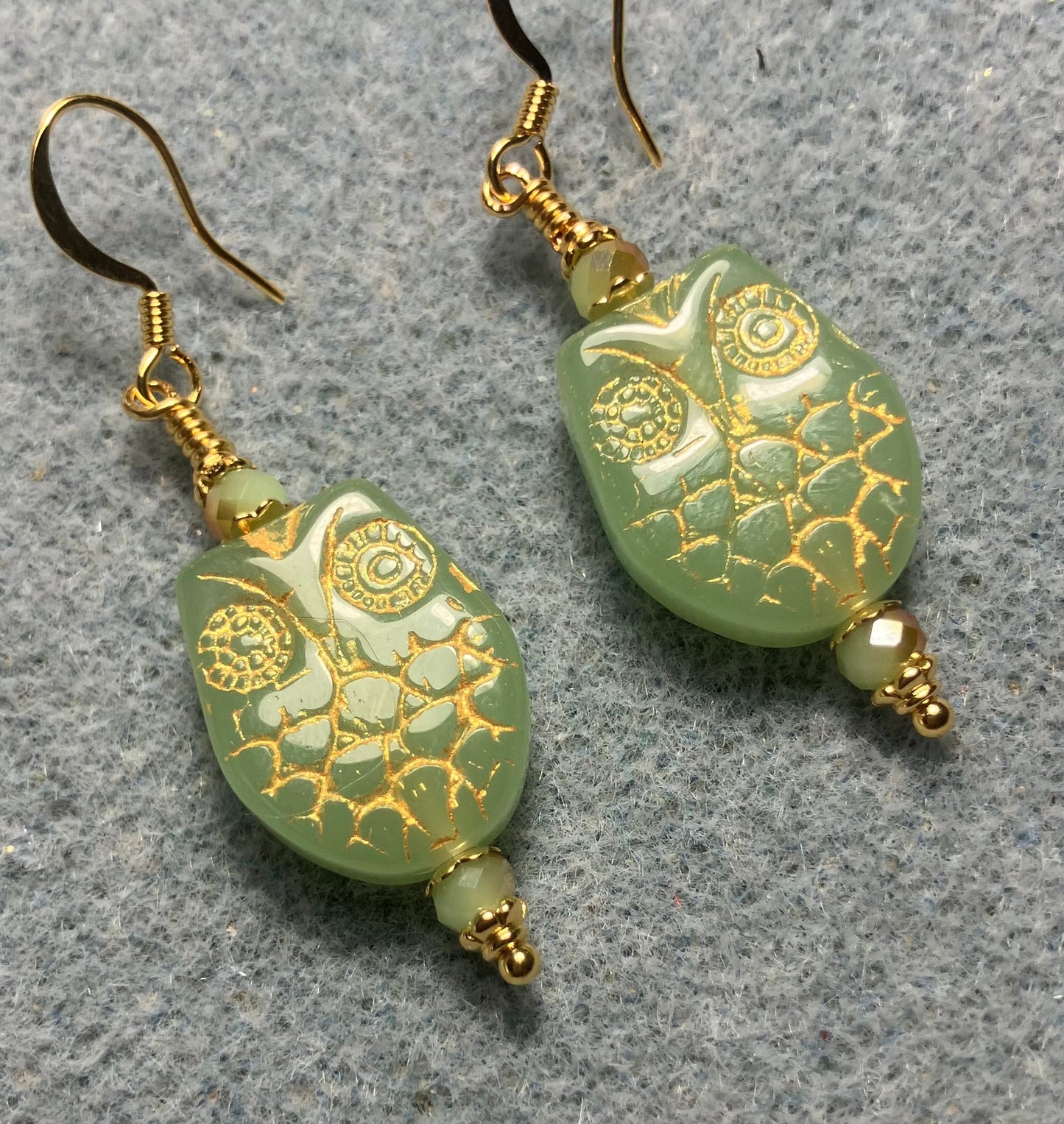 Light green (with gold wash) Czech glass owl bead earrings adorned with light green Chinese crystal beads.