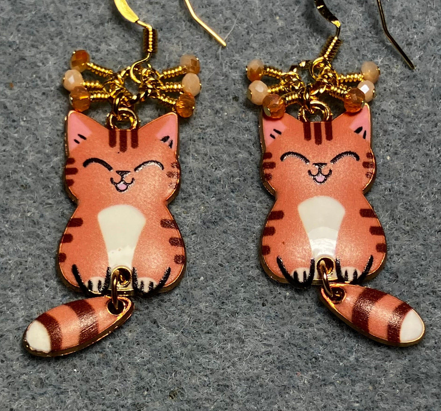 Orange, brown, and white enamel tabby cat charm earrings adorned with tiny dangling orange and white Chinese crystal beads.