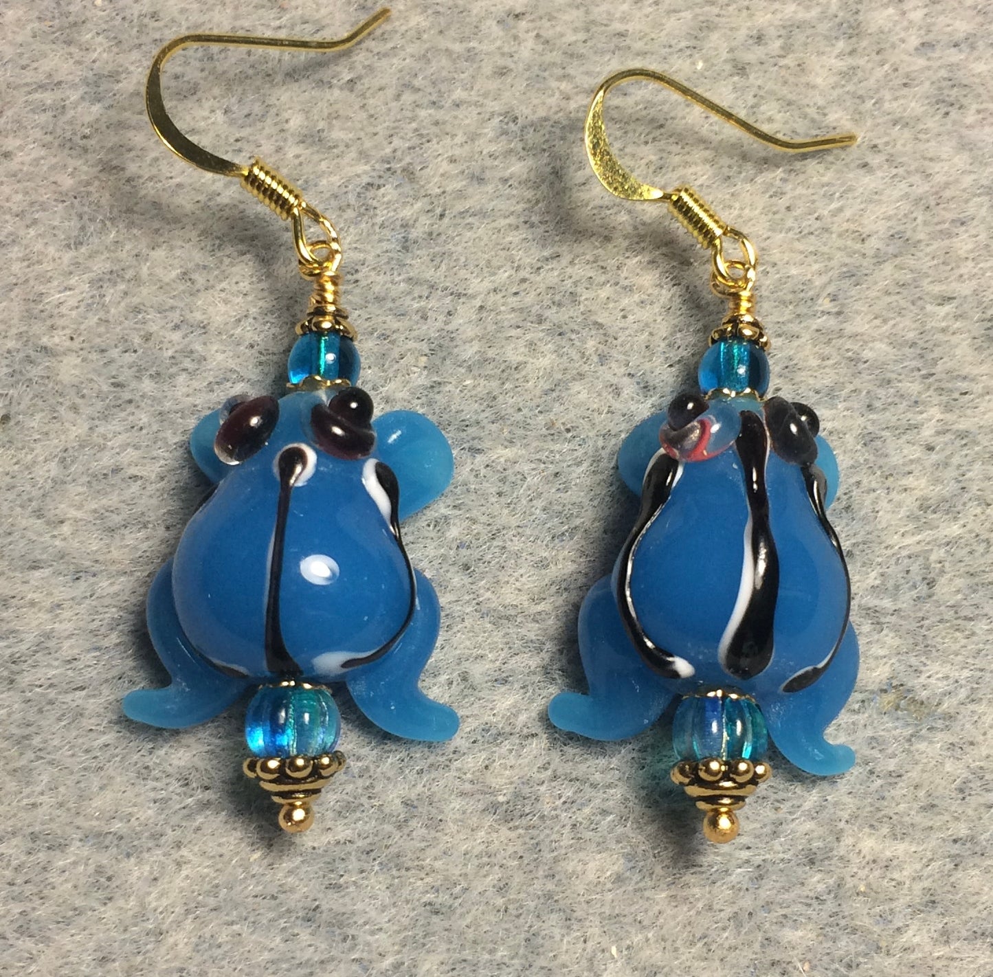 Opaque turquoise blue lamp work striped frog bead earrings adorned with turquoise Czech glass beads.