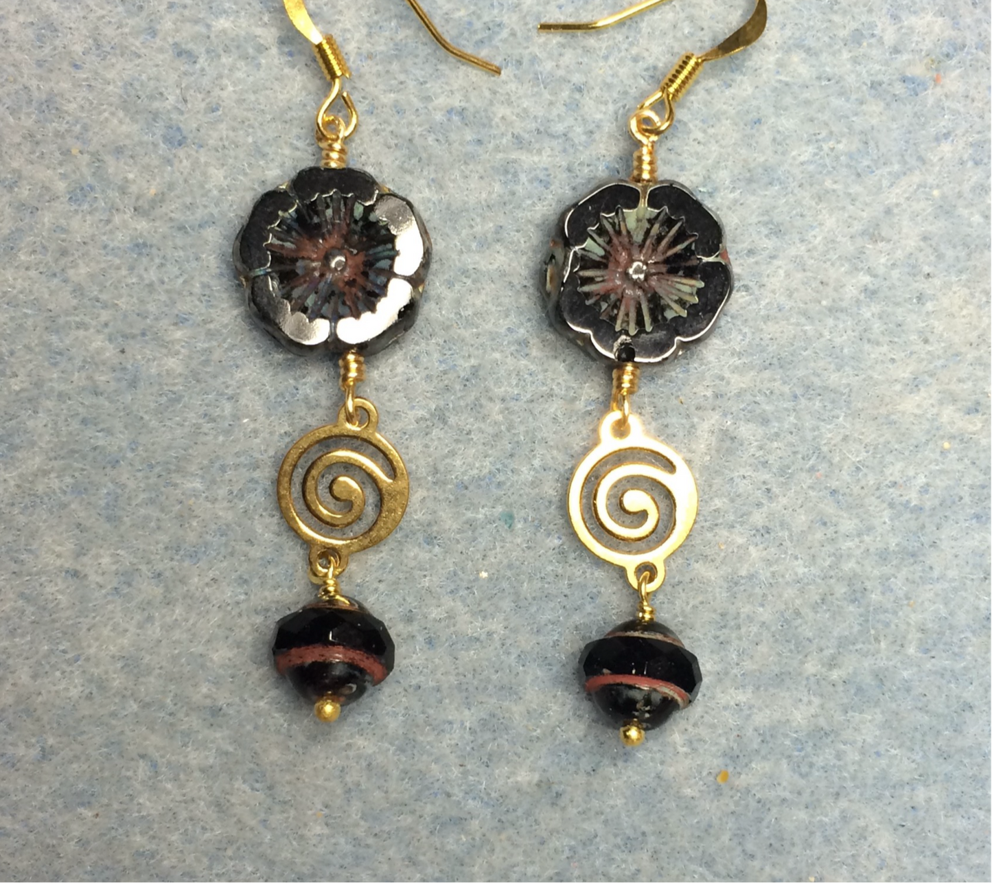 Black Czech glass pansy bead earrings adorned with gold swirly connectors and black Czech glass Saturn beads.