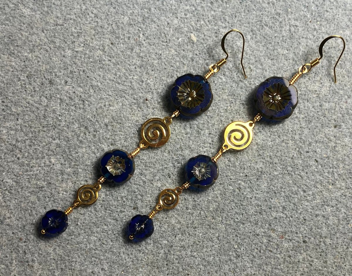 Extra long blue flower bead earrings made with three sizes of cobalt blue Czech glass pansy beads joined by gold swirly connectors.