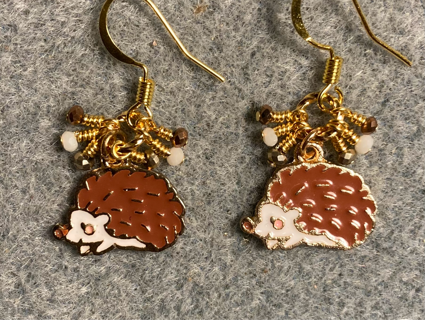 Brown and white enamel hedgehog charm earrings adorned with tiny dangling brown, white, and and gold Chinese crystal beads.
